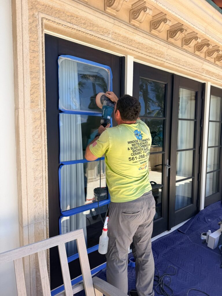Technician polishing French door glass with blue masking tape protecting the frame in Jupiter, FL