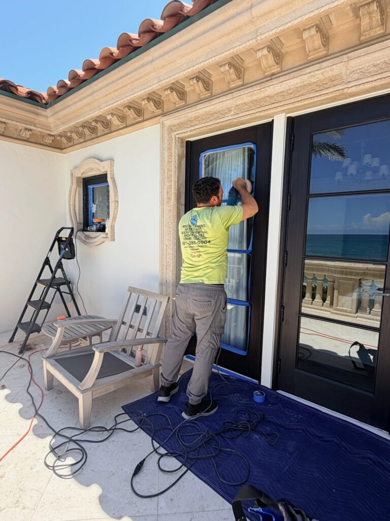 Technician polishing glass on oceanfront French doors in Jupiter, FL